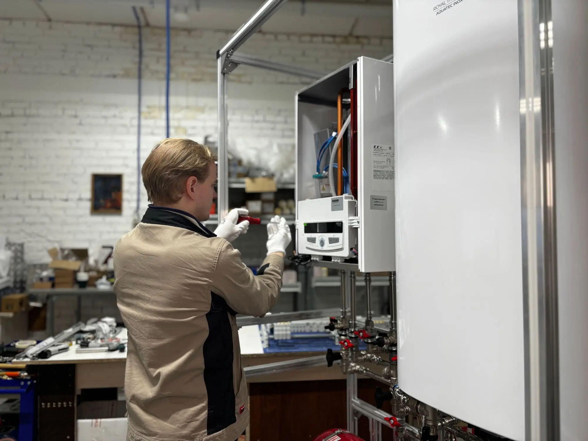 Technik v pracovní bundě nastavuje ovládací panel otevřeného nástěnného kotle